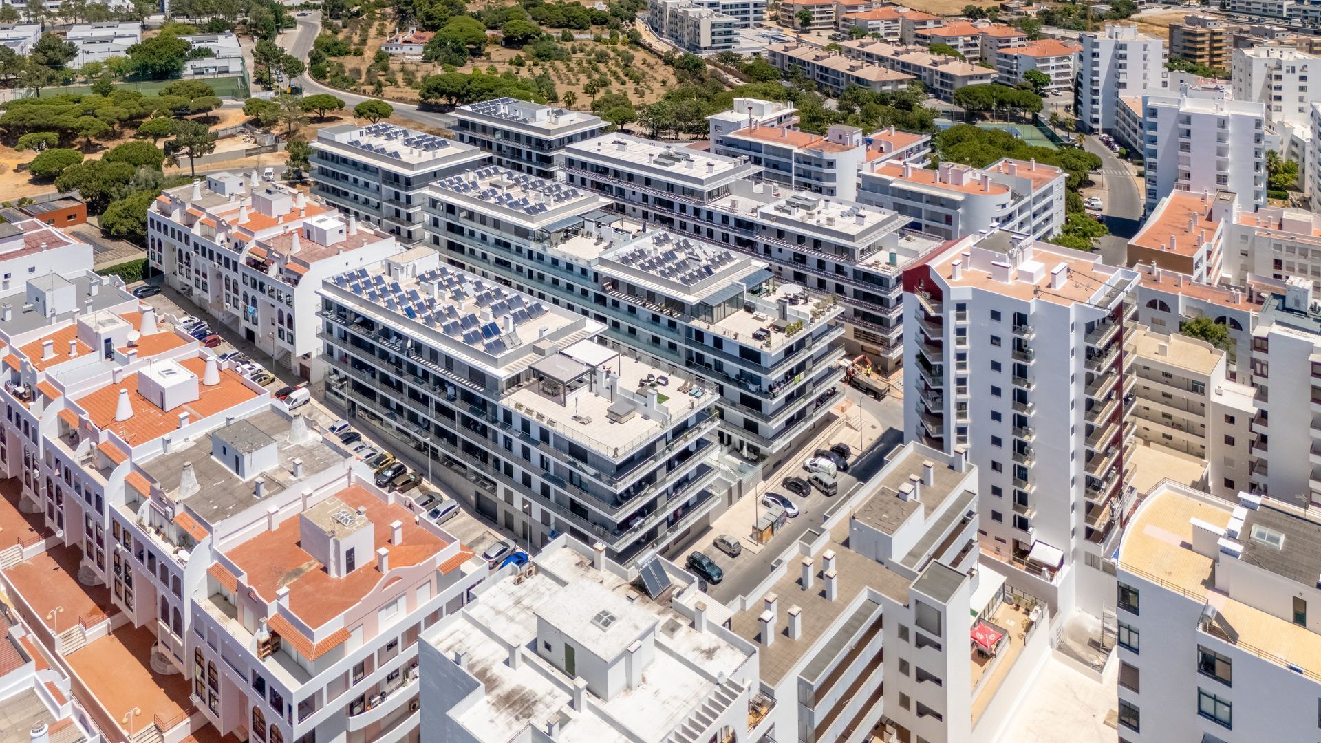 A modern multi-story building with a rooftop parking area and a mix of residential and commercial spaces.