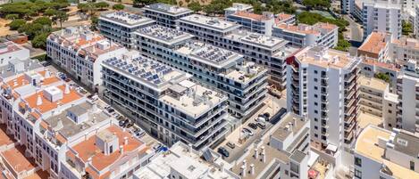 A modern multi-story building with a rooftop parking area and a mix of residential and commercial spaces.