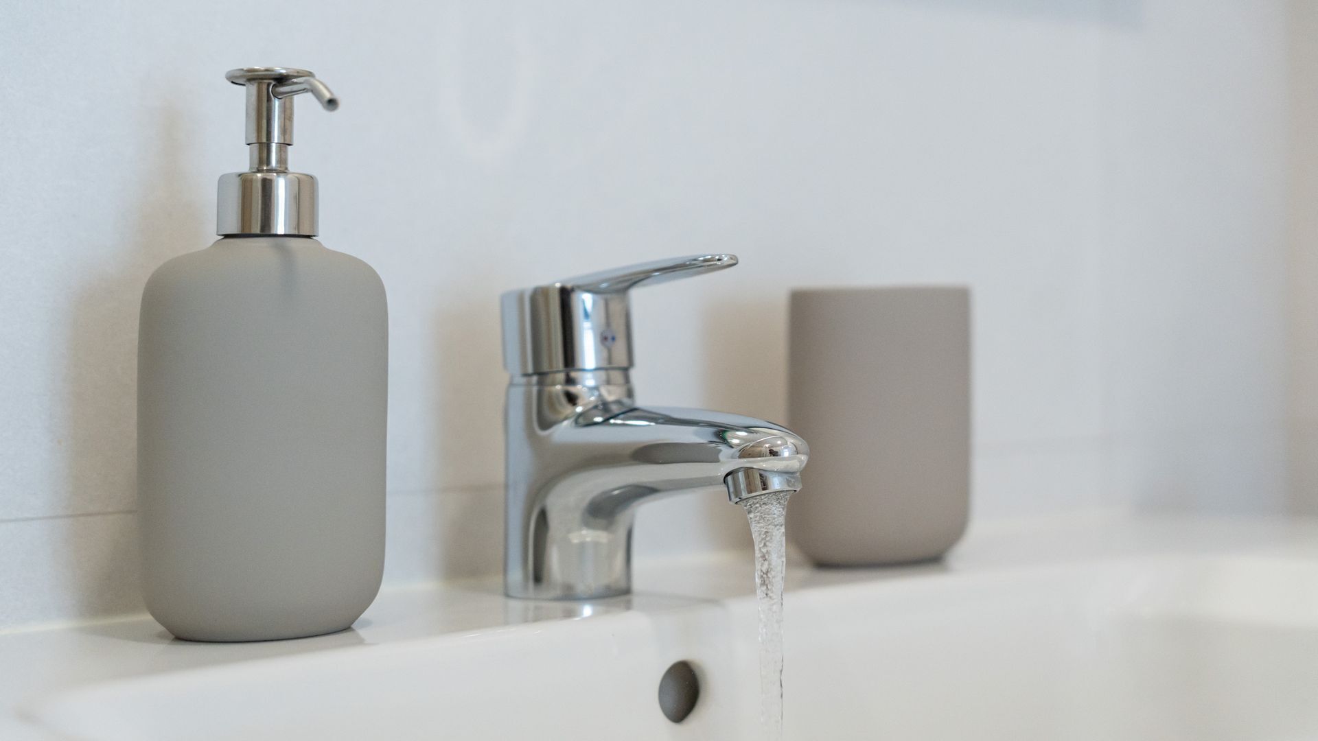 Een wastafel met een chromen kraan en een zeepdispenser.