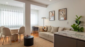 A modern living room with a sofa, a dining table, chairs, a coffee table, and artwork on the wall.