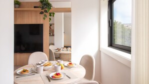 A modern dining area with a round table set for breakfast, featuring plates of pancakes and fresh fruit.