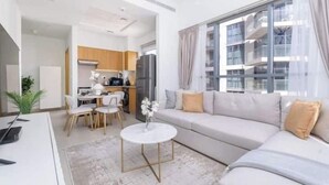 Ein modernes Wohnzimmer mit Sofa, einem Esstisch und einem durchgehenden Gang zur Küche.