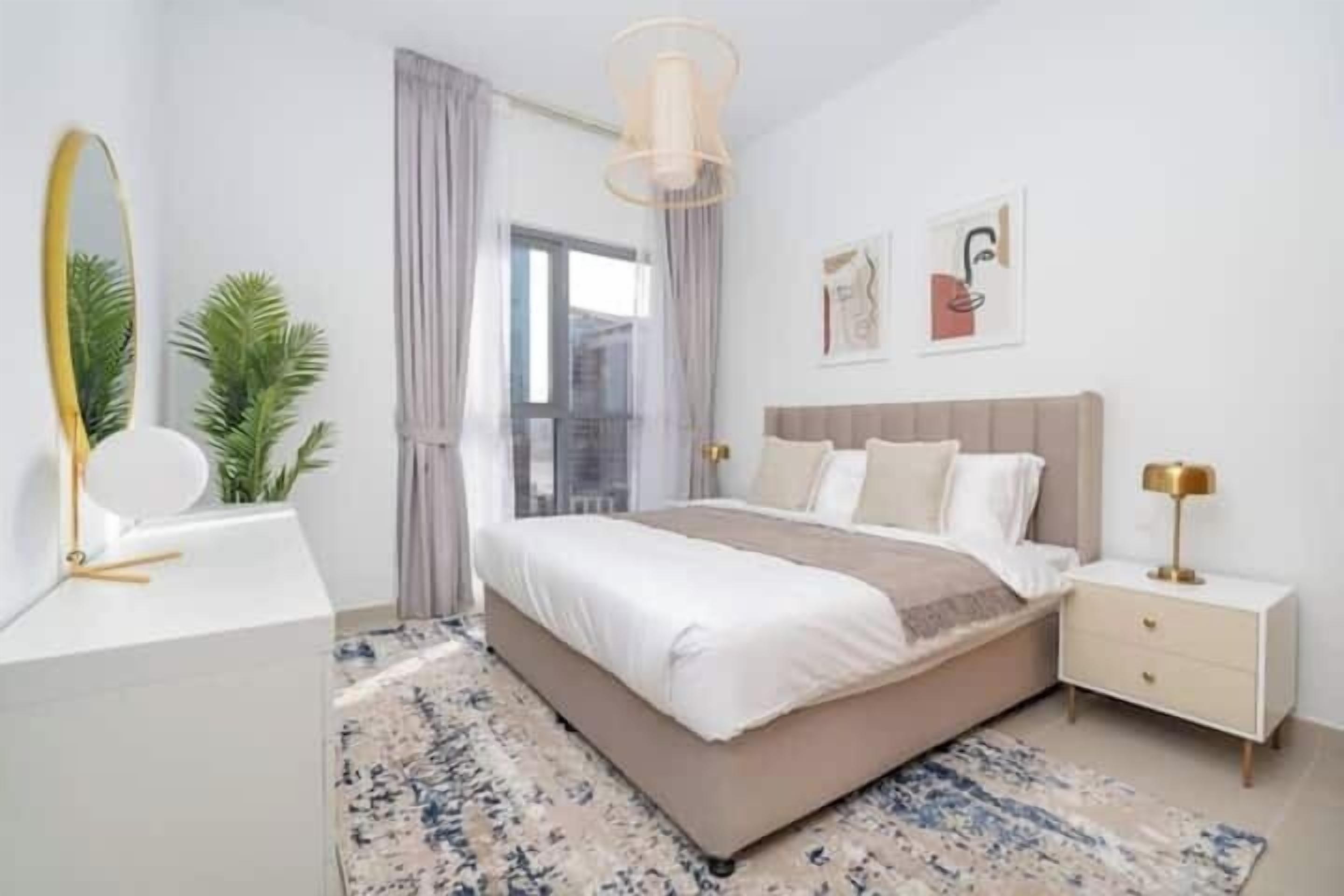 A modern bedroom with a large bed, bedside tables, a mirror, and a view of the outdoors.