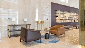 Eine moderne Lobby mit Marmorboden, Ledersofas, einem Glastresen und einem Bücherregal.