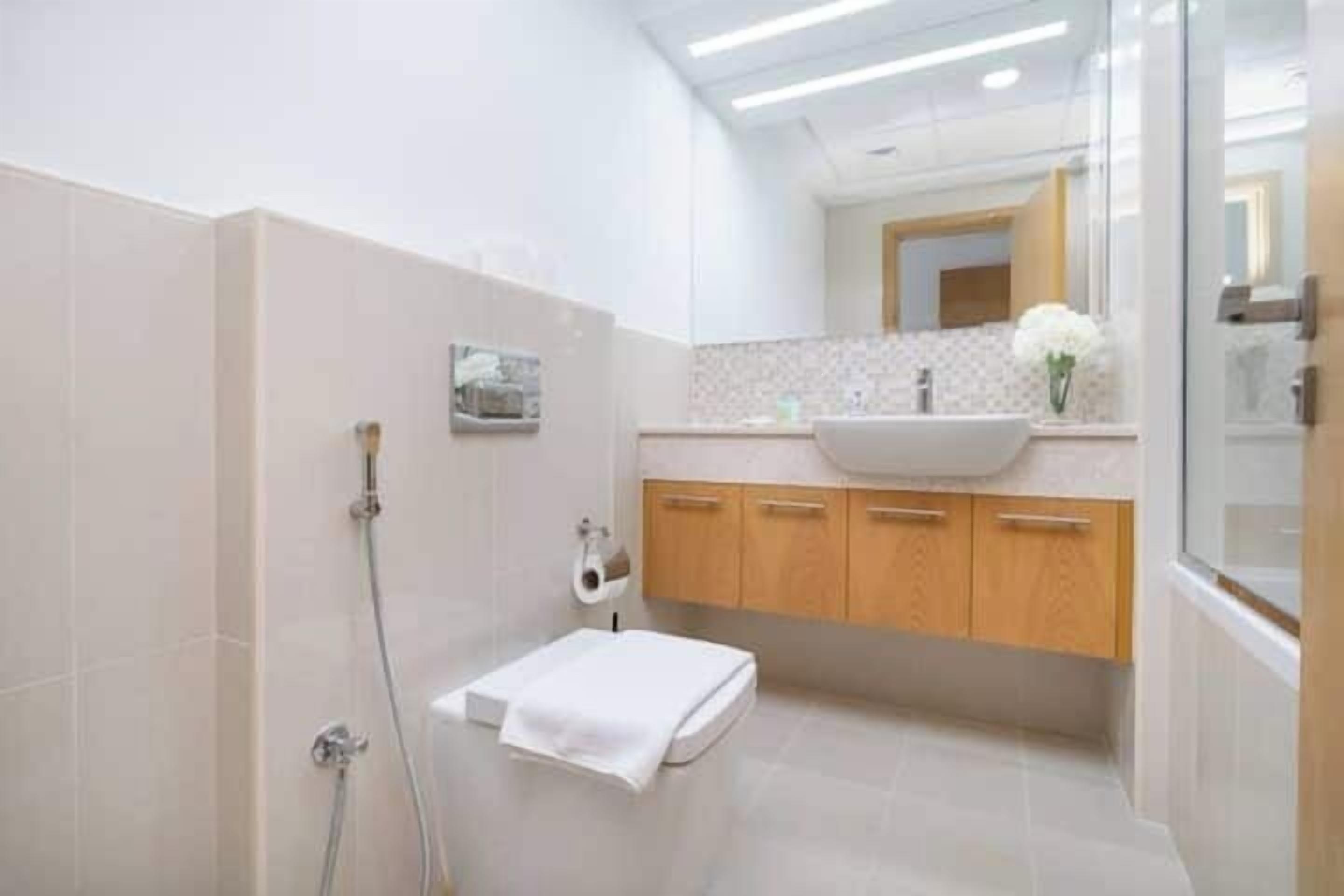 Un baño moderno con cabina de ducha de vidrio, un lavabo blanco y muebles de madera.
