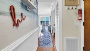 A hallway with a blue patterned rug, a wall-mounted fire extinguisher, and a framed quote. - Beach Escape Top Location w Pool (North Myrtle Beach)