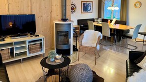 Una sala de estar acogedora con televisión, chimenea, comedor y asientos cómodos.