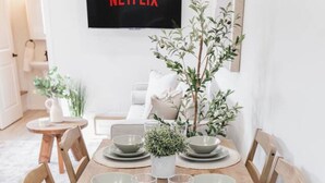 A dining table set with plates, bowls, and glasses, surrounded by wooden chairs. - GarageSuite| 2BD + Ping Pong Fun (Edmonton)