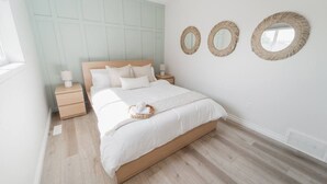 A bedroom with a bed, nightstands, and three wall mirrors. - GarageSuite| 2BD + Ping Pong Fun (Edmonton)