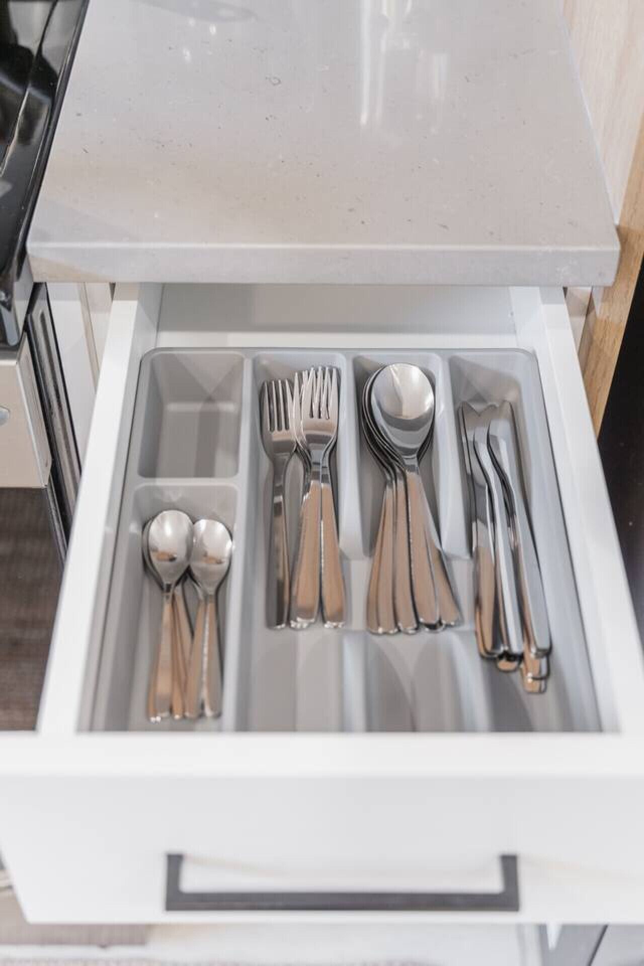 A drawer with neatly organized silverware including forks, spoons, and knives.