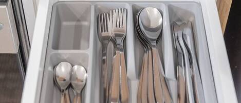 A drawer with neatly organized silverware including forks, spoons, and knives.