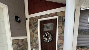 Une entrée de maison avec une façade en pierre, une porte en bois sombre et un paillasson.