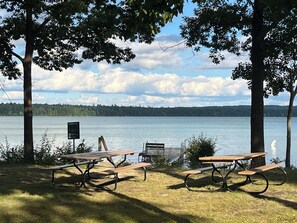 A lakeside picnic area with two picnic tables and a warning sign. - Spacious 4-Bedroom, 3-Bathroom Retreat for Making Special Memories (Interlochen)