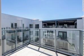 A modern building with a glass balcony, multiple windows, and a flat roof.