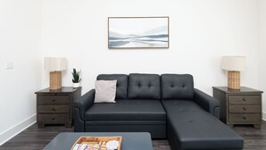 A modern living room with a sectional sofa, two nightstands with lamps, a small plant, and a framed abstract painting on the wall. - 2BR Hollywood Apt w/ Rooftop deck & Stunning Views (Los Angeles)