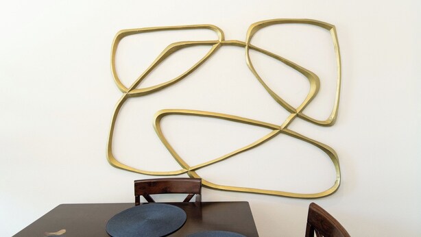 A table with two chairs and a wall-mounted abstract art piece. - 2BR Hollywood Apt w/ Rooftop deck & Stunning Views (Los Angeles)