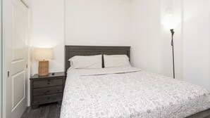A bedroom with a bed, a nightstand, a lamp, and a wardrobe. - 2BR Hollywood Apt w/ Rooftop deck & Stunning Views (Los Angeles)