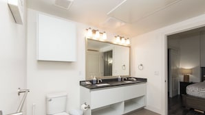 A modern bathroom with a double sink vanity, a toilet, and a large mirror with lights. - 2BR Hollywood Apt w/ Rooftop deck & Stunning Views (Los Angeles)