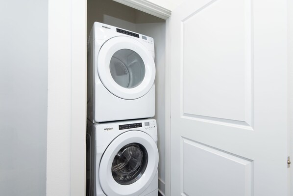A stacked washer and dryer unit in a white-walled room.