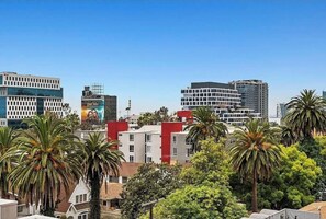 A cityscape with modern buildings, palm trees, and a clear sky. - 2BR Hollywood Apt w/ Rooftop deck & Stunning Views (Los Angeles)