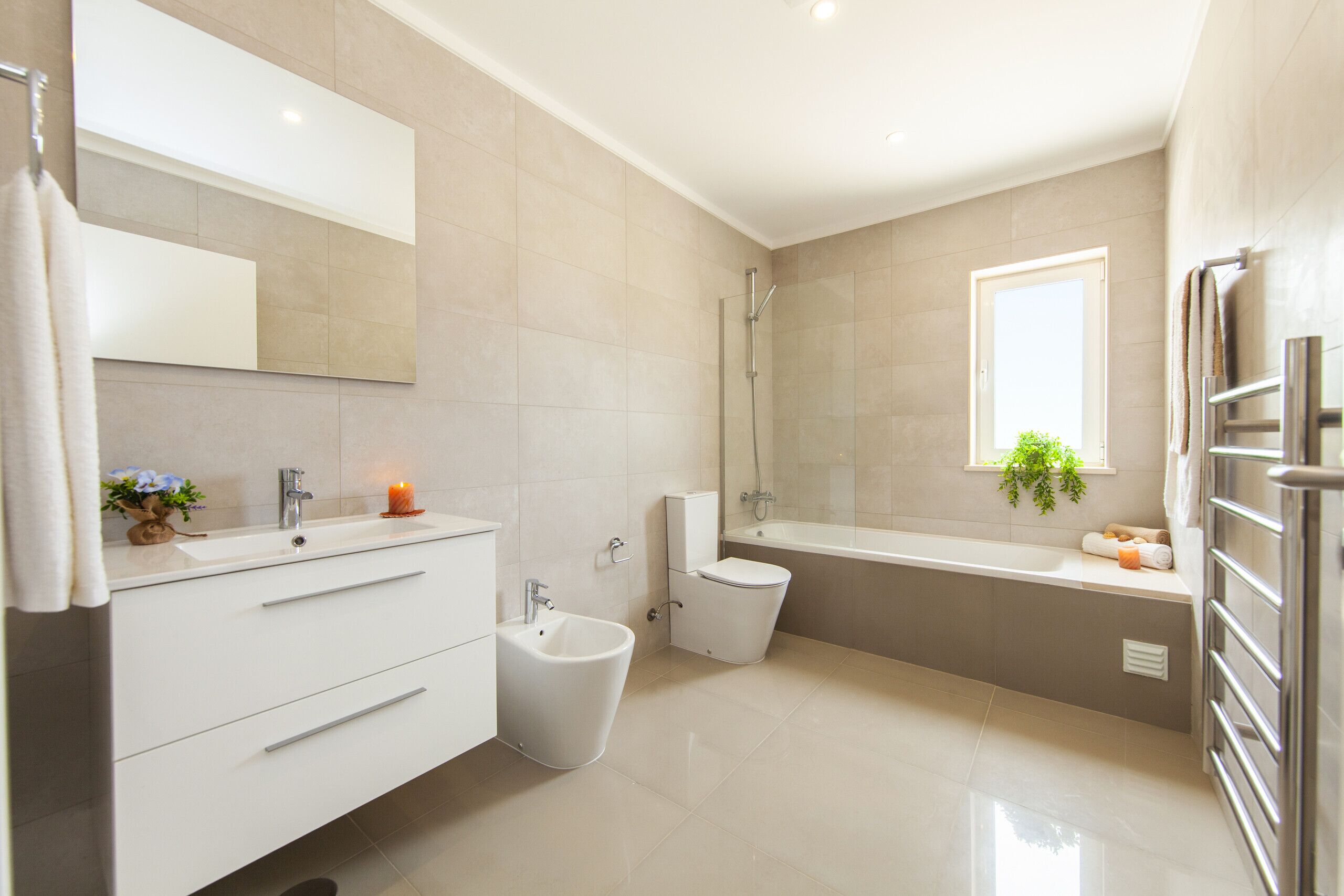 A modern bathroom with a bidet, toilet, and bathtub.