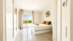 A modern bedroom with a large bed, a view to the outside, and a balcony. - Villa Oasis Gold (Portimão)