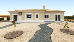 A two-story house with a tiled roof, a driveway with a winding path, and small trees planted in the gravel. - Villa Oasis Gold (Portimão)