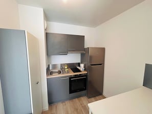 Une cuisine de taille réduite équipée d’un réfrigérateur, d’un four, d’un évier et de placards.