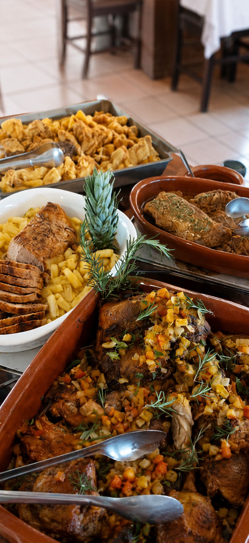 A buffet with various dishes including roasted meats, potatoes, and a pineapple garnish.
