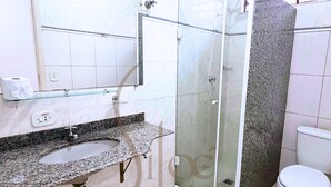 A bathroom with a granite countertop sink, a glass shower enclosure, and a toilet. - Pousada Siloé (Vinhedo)