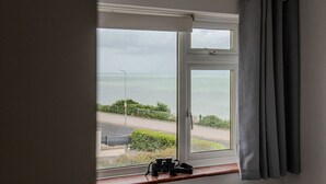 Ein Zimmer mit Fensterblick auf eine Straße und ein Gewässer.