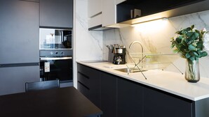 A modern kitchen with a marble countertop, a coffee maker, and a plant.