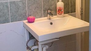 A bathroom with a white sink, a mirror, and a light fixture above the mirror.