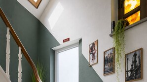 A staircase with white balusters and wooden handrails, leading to a door with a sign above it. - Mixed-gender shared room – Double bed on a loft (Seraing)