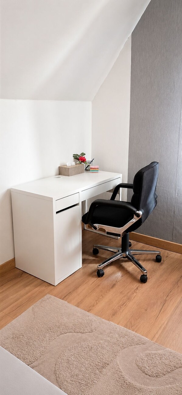 A white desk with a black office chair, a small plant, and a box of tissues. - Mixed-gender shared room – Double bed on a loft (Seraing)