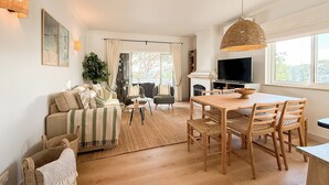 Un salon spacieux comprenant un canapé, une table basse et un coin repas avec une table et des chaises en bois.