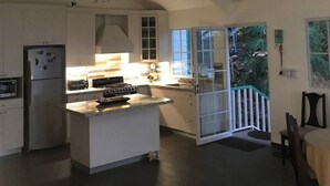 A spacious kitchen with a central island, a dining area with a table and chairs, and a view of the outdoors through a glass door.