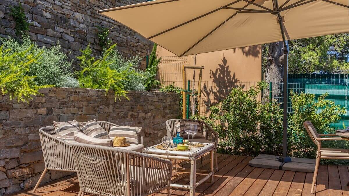 An outdoor patio with wicker furniture, a table set with glasses, and a large umbrella.