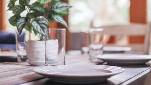 Een eettafel gedekt met borden, glazen en een bloempot.