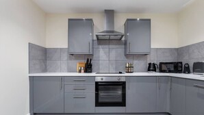 A modern kitchen with grey cabinets, a built-in oven, a microwave, and a coffee maker. - Stirling's Hidden & Tranquil Studio Apartment (Stirling)