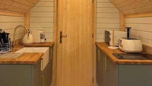 Cocina compacta con gabinetes de madera, un lavamanos, un tostador y una lámpara sobre la puerta.