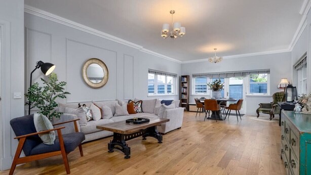 A spacious living room with a sofa, coffee table, and a dining area with chairs and a table.
