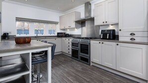 A modern kitchen with white cabinets, a gas stove, a microwave, and a coffee maker.