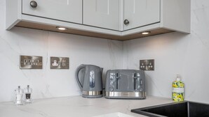 A modern kitchen with white cabinets, a stainless steel kettle, a toaster, and a sink. - The Stirling Penthouse - Free Parking (Stirling)