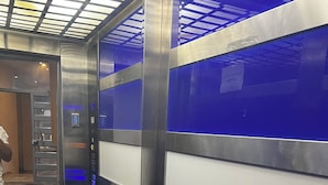 An elevator interior with blue and white panels, a control panel, and a digital display.