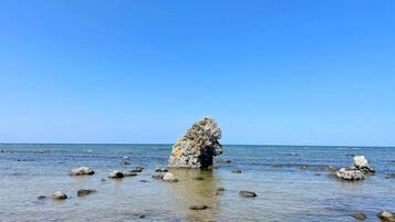 A clear view of a rocky shoreline with calm water and a clear sky.