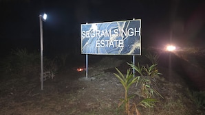 A sign for Segram Singh Estate at night with minimal surrounding vegetation.
