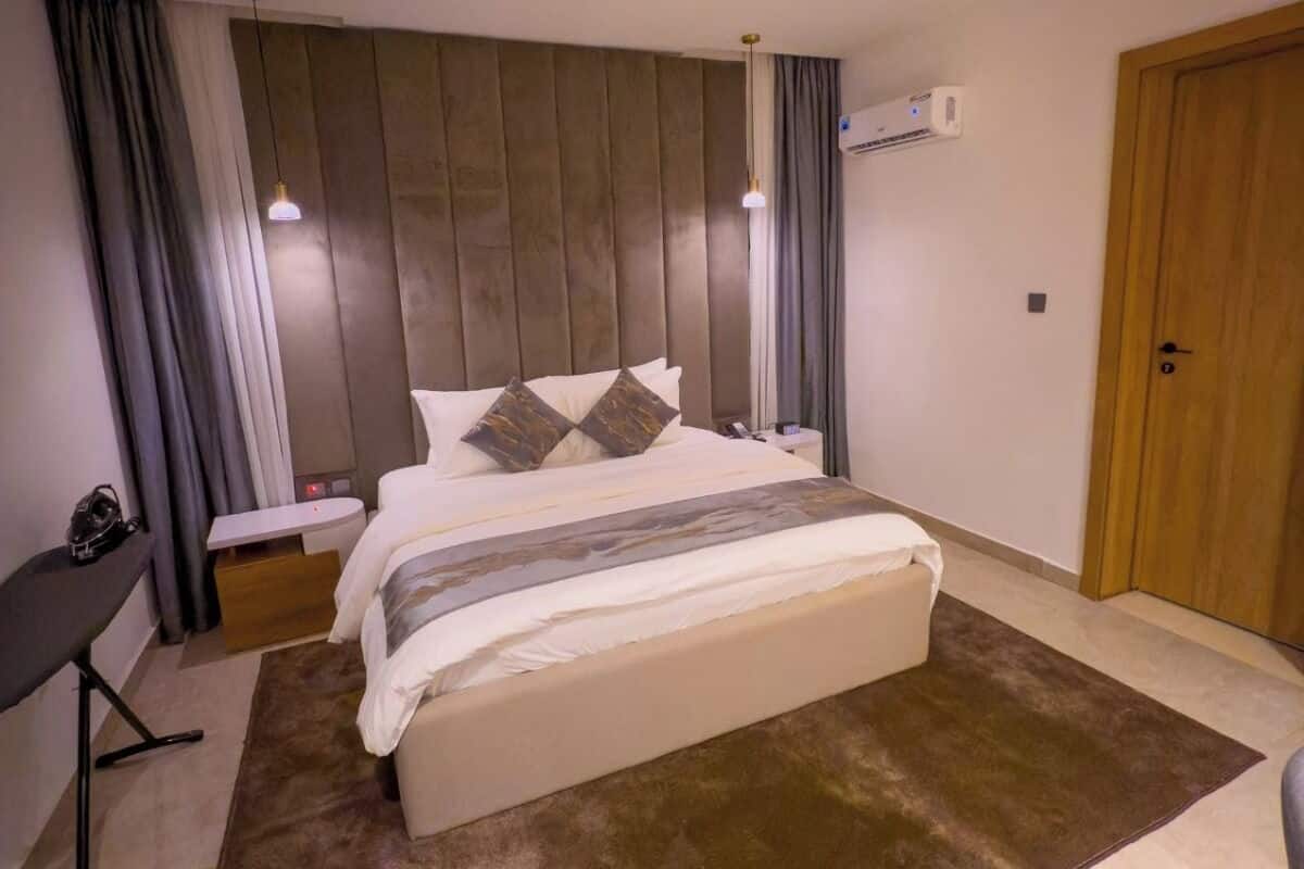 Ein modernes Hotelzimmer mit einem großen Bett, Nachttischen, einem Schreibtisch und einer Klimaanlage.
