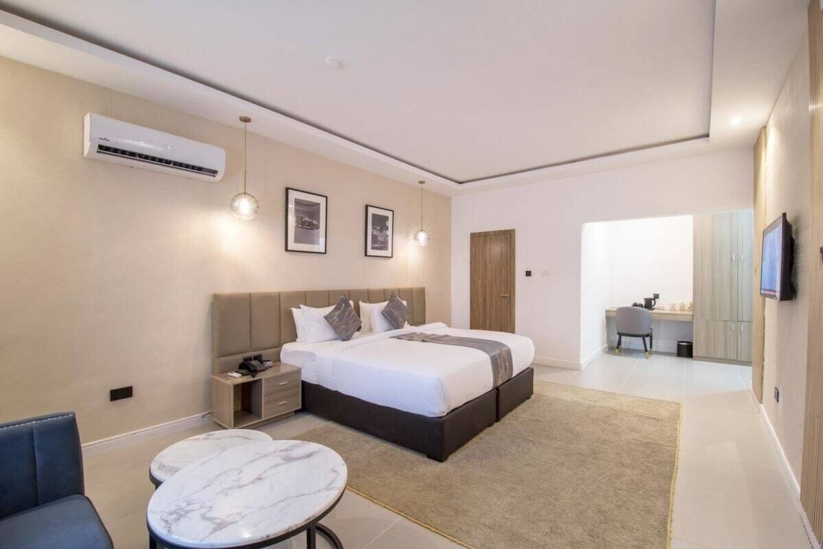 Ein modernes Schlafzimmer mit Bett, Nachttischen, Schreibtisch und Fernseher.