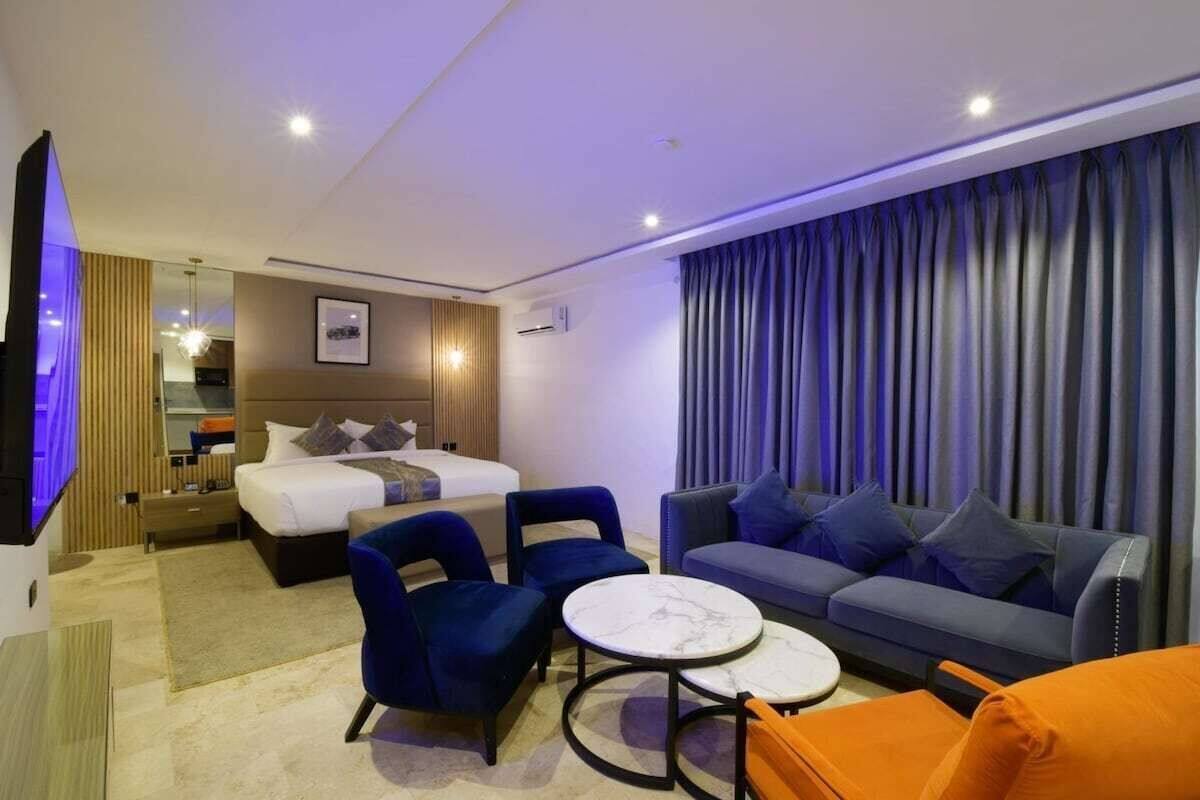Ein modernes Hotelzimmer mit einem Bett, zwei Sofas, einem Couchtisch und einem Fernseher.
